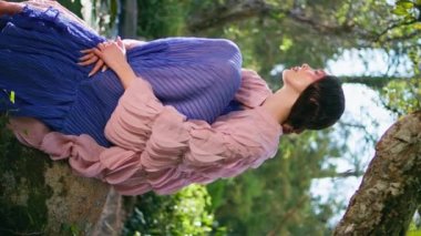 Büyülü Orman Gölü 'nde poz veren kız harika bir yaz günü. Yeşil ağacın altında oturan romantik büyüleyici kadın güzel gölet suyu dikey görüntüsü veriyor. Nazik masal modeli, doğanın sakinliğinin tadını çıkar..