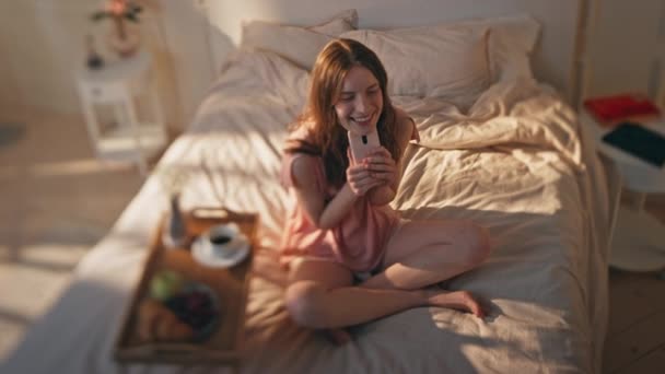 Gelukkige Tiener Houden Smartphone Rusten Zonnige Slaapkamer Dromerig Model Genieten — Stockvideo