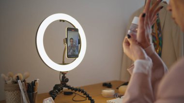 Stüdyoda kozmetik ürünleri sergileyen Vlogger elleri. Güzellik blogcusu kız oda içi sıvıyı çıkarırken yüzünü gösteriyor. Nüfuzlu kadın telefon kamerasında günlük kişisel bakım programını çekiyor.