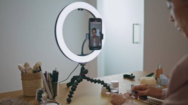 Medya çalışanı evde akıllı telefon ekranından bahsediyor. Makyöz, cep telefonuna halka lambasının üzerine makyaj yapılmasını öneriyor. Tripoda cep telefonu kullanan mutlu kadın güzellik blogu oluşturuyor