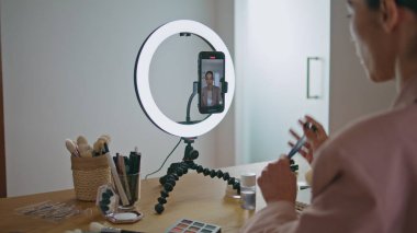 Makyaj sanatçısı evde cep telefonu görüntüsünü gözden geçiriyor. Kapanışı yapan ünlü konuşmacı abone öğretmenlik yapıyor içeride blog yayınlıyor. Kadın güzellik blogcusu sosyal medyada bilgi paylaşıyor. Canlı yayın