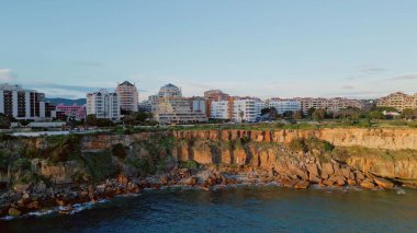İnsansız hava aracı manzaralı kompleks yaz deniz manzarası. Yüksek uçurum kıyısındaki panoramik sahil beldesi. Sakin okyanus dalgaları kayalık sahilde ağır çekimde. Volkanik deniz tepeleri deniz manzarası