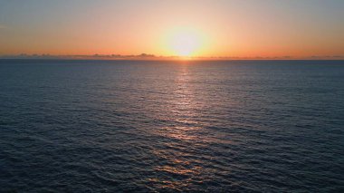 Turuncu günbatımı deniz ufku insansız hava aracı manzarası. Panoramik pembe siluet dalgalanan sakin dalgalar. Gün batımının sakin ve sulu sulara yansıması. Sonsuz manzaralı okyanus doğası. Meditasyon gevşeme kavramı
