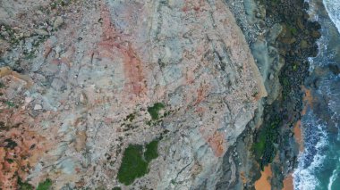 Köpüklü okyanus sörfü kıyı kayalarını parçalıyor. Plajı kaplayan sisli deniz çok yavaş çekimde. Sisli hava kasvetli dramatik kıyılar. Beyaz dalgalar volkanik çakıl taşlarını yıkayan gri tek renkli deniz manzarası