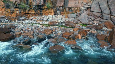 Köpüklü okyanus kayalıkları yakın çekim yıkıyor. Güçlü fırtınalı deniz sörfü yüksek dağlara çarpıyor. Dalgalar tehlikeli kahverengi kayalarda su patlaması yaratıyor. Beyaz dalgalar kıyıya vuruyor