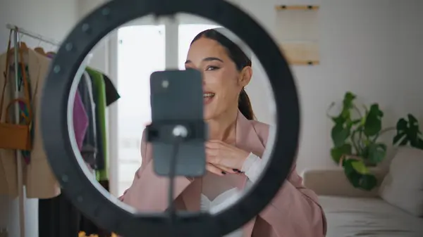 Blogger woman filming makeup tutorial using cellphone at house closeup. Talking influencer girl gesturing hands live streaming in home with professional lighting equipment. Cosmetics product review