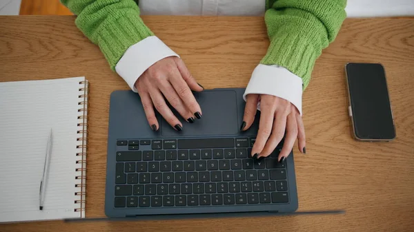 Unrecognizable woman working laptop in home office close up. Lady hands typing computer scrolling touchpad alone indoors. Unknown businesswoman searching information in internet using modern device