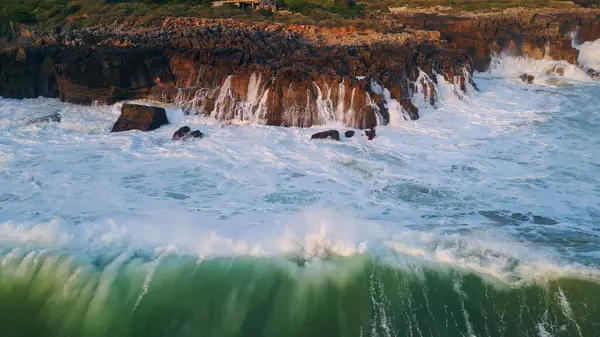 强大的海浪冲刷着悬崖空中的景色 泡沫汹涌的海水冲刷着高高的石山特写 汹涌的海浪造成海上爆裂岩石慢动作 海岸的飞溅 — 图库照片
