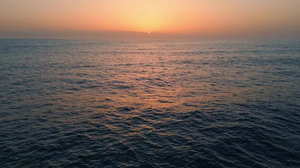 Panoramic dawn marine landscape drone view. Pastel pink skyline serene surf rippling. Orange sunset reflecting in calm lapping water. Endless scenic ocean horizon. Meditation relaxation themes concept