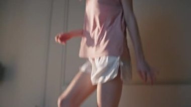 Güneş ışığında yatak odasından atlayan ince bacaklar. Enerjik neşeli kadın kulaklıkla en sevdiği müziği dinliyor, tek başına dans ediyor. Heyecanlı gülümseyen genç içeride özgürce eğleniyor..