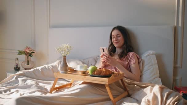Glädjande Kvinna Bläddrar Mobiltelefon Bekväm Säng Lugn Flicka Njuta Morgon — Stockvideo