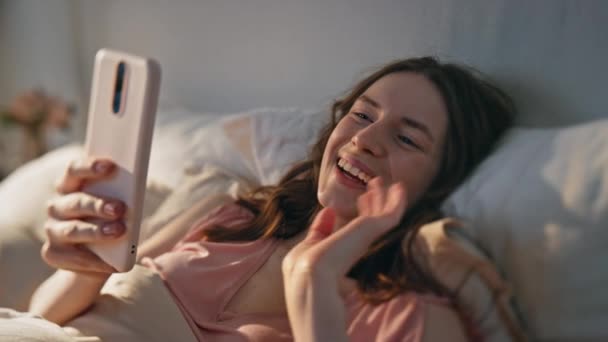 Menina Fazendo Videochamada Cama Closeup Sorrindo Mulher Feliz Acenando Smartphone — Vídeo de Stock