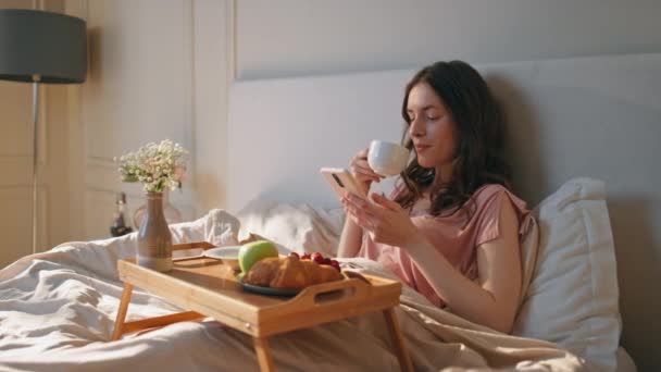 Hemmaflickan Njuter Morgonkaffe Helgen Avslappnad Kvinna Som Håller Smartphone Liggande — Stockvideo