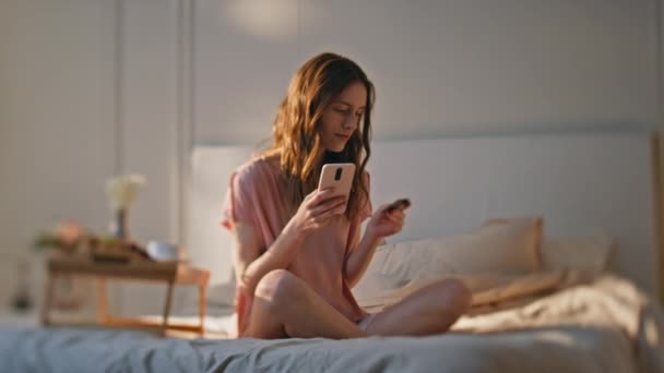 Smiling Woman Making Payment Sunny Bedroom Relaxed Girl Resting Weekend — Stock Video