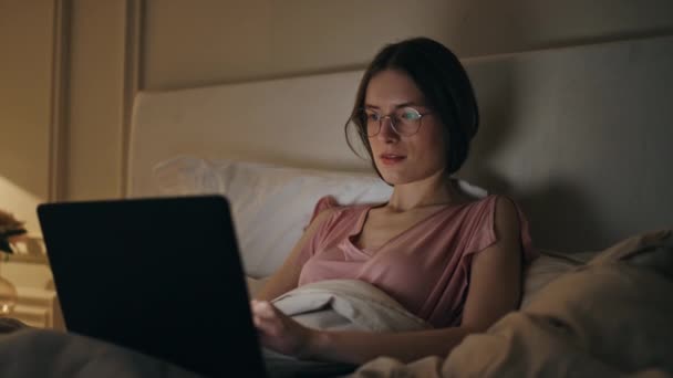 自宅の夜のクローズアップでラップトップを閲覧する楽しい女性 笑顔の少女は 睡眠前にオンラインでチャットするメッセージを入力します フリーランサーの作業コンピュータが遅れてプロジェクトを作成します 週末の夕方にハッピーな女性チル — ストック動画