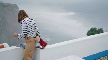 Yaz tatilinde deniz kenti çatısında dinlenen bir kız. Çarpıcı Akdeniz kıyıları. Güzel turist öğrenci, şehri keşfetmek için görüş açısını terk ediyor. Düşünceli güzel kadın fotoğrafçı eski köyde yürüyor..