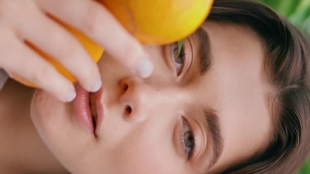 女人面对橙色水果的绿色垂直肖像 自信华丽的姑娘凝视着植物园 快乐的性感黑发在橘子种植园享受夏天的放松 — 图库视频影像