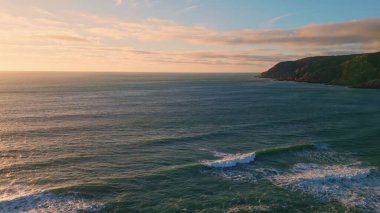 Sakin okyanus yüzeyi ağır çekimde kabarır. Resmedilmeye değer yeşil tepeler sakin deniz dalgalarıyla yıkanır. Akşam köpüklü dalgalar kıyıya vuruyor. Vahşi terk edilmiş kıyı manzarası konsepti