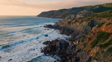 Uçan kayalık deniz manzarası köpüklü deniz dalgaları kıyı şeridini yavaş çekimde kırıyor. Mavi okyanus suyu tehlikeli kayalıklara sıçrıyor. Deniz manzarası taştan kıyı manzarasında dalgalanır.