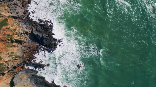 俯瞰的海浪以超慢速的速度向崎岖的海岸悬崖飞去 无人机向岩石海岸线喷射出美丽而强大的海水 冲撞着岩石海岸 阳光明媚的海洋风景危险的粗糙海岸线 — 图库照片