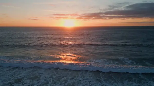 Golden dawn sky over serene ocean surf. Aerial view sunset dark sea rippling water surface. Picturesque swell peaceful waves moving at evening sundown slow motion. Meditative calm marine scenery