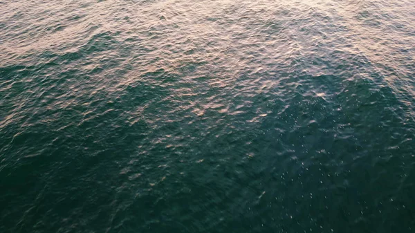 Marine water waving surface reflecting sun beams close up. Deep blue liquid rippling under sunny sky slow motion. Aerial view picturesque ocean lapping at day light. Tranquil sea waves moving slowly