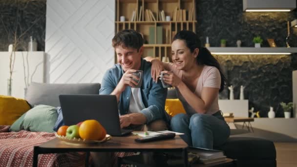 Ζευγάρι Γελώντας Βλέποντας Ταινία Στο Σπίτι Χρησιμοποιώντας Σύγχρονο Φορητό Υπολογιστή — Αρχείο Βίντεο