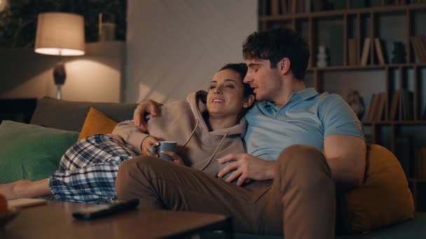 很喜欢家人一起看电视 深夜坐在舒适的沙发上 快乐浪漫的夫妻在舒适的客厅里谈论电影的放松 释放出来的年轻夫妇在家里度周末 — 图库视频影像