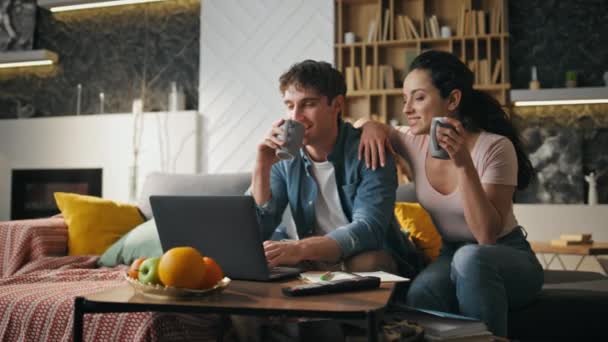 Oturma Odasında Kahve Içen Çift Dizüstü Bilgisayara Bakıyor Kaygısız Eşler — Stok video