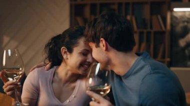 Romantik partnerler şarap içip gülüyor, evde birlikte eğleniyorlar. Mutlu eşleri sevmek, gece geç saatlerde rahat bir dairede buluşmanın keyfini çıkarmak. Gülen çift tatilleri alkolle kutluyor..