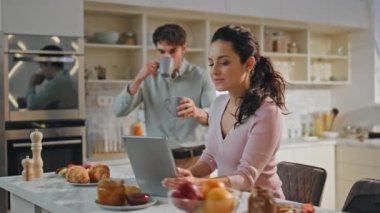 Sabah kahvesini yudumlarken çekilmiş birkaç video. Gülümseyen genç eşler tablet bilgisayarda toplanıp yemek yiyorlar. Kahvaltıda web kamerasına mutlu aile selamı.