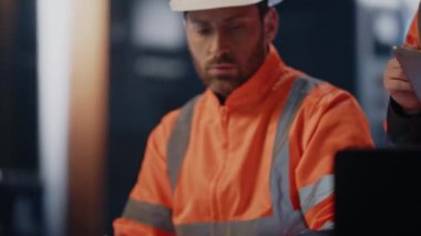 Metalurji fabrikasında çalışan iki teknisyen teknik belgeleri tartışıyorlar. Tabletli kadın patrona kağıtları gösteren bir dizüstü bilgisayar mühendisi. Üniformalı uzmanlar takım çalışması.