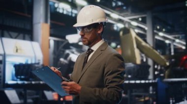 Ciddi bir yönetici üretim atölyesindeki üretim sürecini tek başına yakından kontrol ediyor. Koruyucu miğfer fabrikasındaki kendine güvenen müfettiş kontrol listesine not alıyor. İş denetimi kavramı