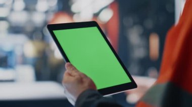 Yeşil ekran tableti tutan işçi elleri üretim bilgilerini yakından inceliyor. Tanımlanamayan mühendis model bilgisayarda üretim sırasını kontrol ediyor. Krom anahtar kullanan profesyonel fabrika işçisi.
