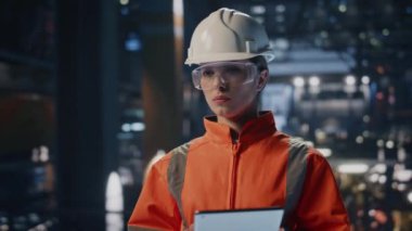 Kadın denetleyici, fabrika üretim tesisini tabletle kontrol ediyor. Profesyonel kadın müfettiş üretim makinelerini arıyor. Kask üniformalı mühendis bilgisayardan not alıyor..