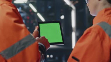Ağır sanayi tesislerinde yeşil ekran tableti izleyen fabrika arkadaşları. Mockup pad bilgisayarında verileri analiz eden iki bitki uzmanı. Aleti işaret eden birkaç üretim işçisi