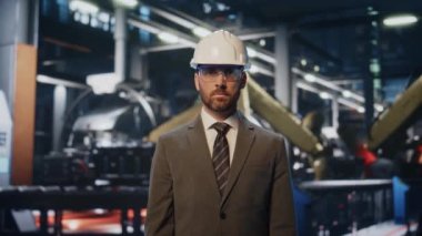 Modern üretim atölyesinde duran ciddi bir fabrika sahibinin portresi. Metalurji makinesinin önünde kendine güvenen sakallı bir iş adamı var. Akıllı mühendis imalatta poz veriyor.