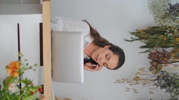 Bizneswoman Rozmawiać Telefon Komórkowy Kwiaciarni Pionowe Skoncentrowany Laptop Pracy Przedsiębiorcy — Wideo stockowe