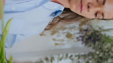 Ciddi bir çiçekçi çiçekçiye dikey olarak çiçek hazırlar. Güzel kadın sahibi çiçekçi dükkanında çiçek buketi kesmiş. Genç odaklı kız çiçek kompozisyonu yapıyor. Çiçekçilik başlangıç konsepti.