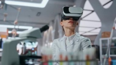 Laboratuvar uzmanı klinikte gözlük takarak sanal gerçeklik arayüzüne dokunuyor. VR gözlüklü kadın nörolog fütüristik simülasyonla bilimsel araştırma yapıyor. Doktor siber uzayda çalışıyor..