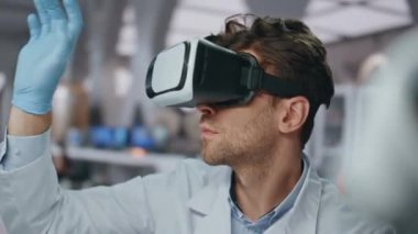 Gözlüklü bilim adamı nörobilim laboratuvarında sanal gerçekliği kontrol ediyor. VR gözlükleri araştırmasında çalışan yetenekli bir kimyager. Profesyonel mikrobiyolog eldivenlerle arayüzü elle soyuyordu.