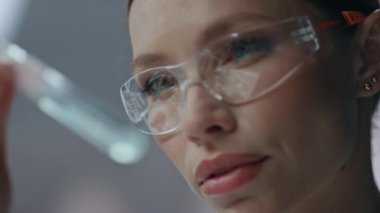 Klinik uzmanı test tüpü laboratuarında aşı örneği araştırıyor. Güvenlik gözlüklü kadın bilim adamı deneysel ilaçları inceliyor. Ciddi bir araştırmacı yüzü deney kabında ilaç arıyor.