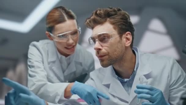 临床专家在创新实验室的试管中探索药物 笑着让两位科学家为成功的研究疗法感到高兴 戴手套的女研究员讨论科学实验 — 图库视频影像