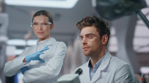 两名实验室同事微笑着在高级诊所拍照 在创新实验室的安全眼镜中的成功科学家的肖像 现代医院中快乐的专业生物化学家 — 图库视频影像