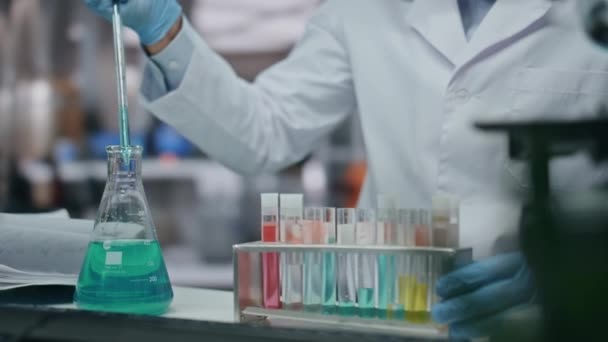微生物学者の手で 薬理学のクリニックラボで働いてる 実験薬を用いた試験管を充填する専門研究者 医学実験をする手袋の男科学者 — ストック動画