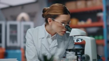 Bilim laboratuarında mikroskop araştırması yapan başarılı bir kimyager. Modern klinikte kameraya gülümseyen mutlu kadın laboratuvar uzmanı portresi. Tıbbi araştırmalarda çalışan güzel kadın bilim adamı..