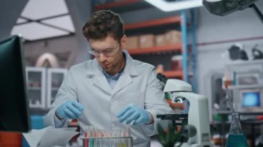 Tıbbi teknisyen, hastalığın yakın çekiminden elde edilen yeni aşıyı araştırıyor. Deney tüpü tutan odaklanmış bilim adamı mikroskoba bakıyor. Bilgisayar ekranındaki verileri kontrol eden genç bir araştırmacı