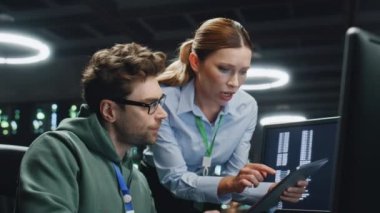 Karanlık sunucu odasında çalışan veri merkezi analistleri. Bilgisayar uzmanı kadın patrona analitik verileri gösteriyor. İki programcı izleme ofisindeki siber güvenliği tartışıyorlar