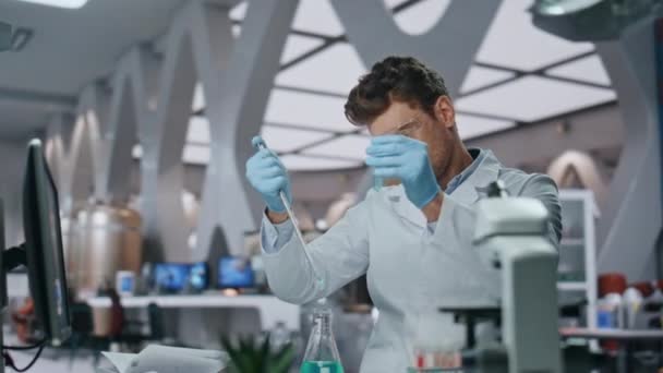 高度な研究室で専門知識を生み出す化学者が近づいている ピペットで満たされたテスト管を調べる集中された男性の研究者 実験室でウイルス実験を行った若い賢い科学者 — ストック動画