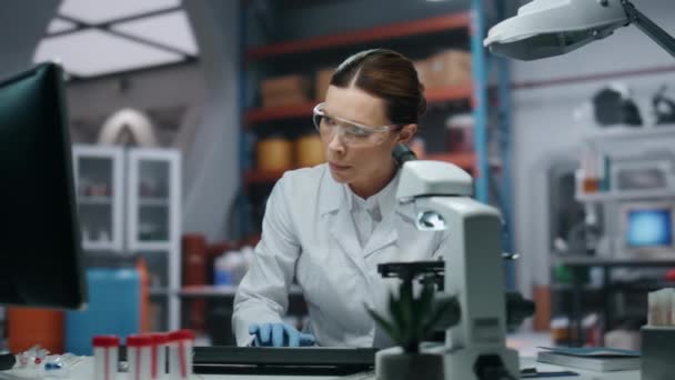 在医学实验室工作的认真的科学家对计算机进行了近距离研究 女生物化学家研究药物监测数据 眼镜生物技术工作者专注于科学研究 — 图库视频影像